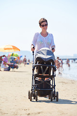 Image showing mother walking on beach and push baby carriage