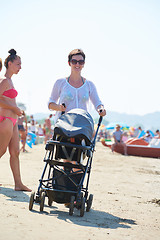 Image showing mother walking on beach and push baby carriage