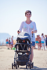 Image showing mother walking on beach and push baby carriage