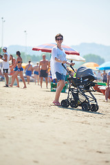 Image showing mother walking on beach and push baby carriage