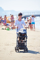 Image showing mother walking on beach and push baby carriage