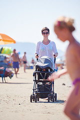 Image showing mother walking on beach and push baby carriage