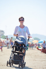 Image showing mother walking on beach and push baby carriage