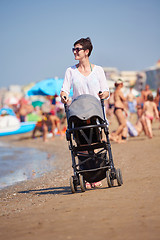 Image showing mother walking on beach and push baby carriage