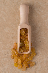 Image showing Wooden scoop with golden raisins