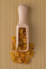 Image showing Wooden scoop with golden raisins
