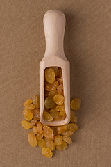 Image showing Wooden scoop with golden raisins