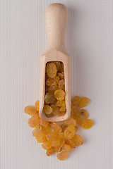 Image showing Wooden scoop with golden raisins