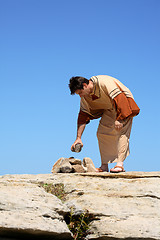 Image showing Man picking up rock or making rock pile.