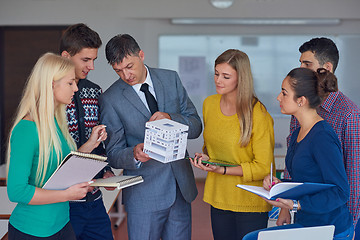 Image showing group of students working with teacher on  house model