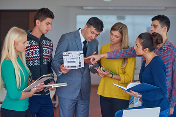 Image showing group of students working with teacher on  house model