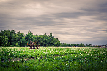 Image showing Water pump on a green field in dark weather