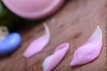 Image showing sea salt, spa stones and flower petals on wooden table, closeup