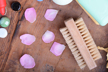 Image showing comb, sea salt, spa stones and flower petals on wooden table, closeup