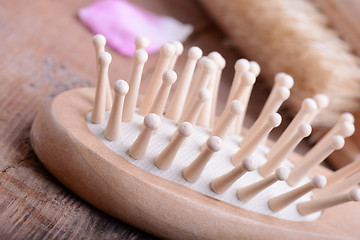Image showing hair brush, rose flower petals, comb on wooden plate. close up