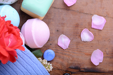 Image showing sea salt, spa stones, towels, soap and flower petals on wooden table, closeup