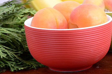 Image showing bananas and apricots on red plate, close up