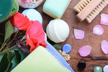 Image showing comb, sea salt, spa stones and flower petals on wooden table, closeup