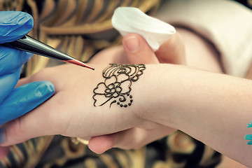 Image showing A tattoo artist applying his craft onto the hand of a female