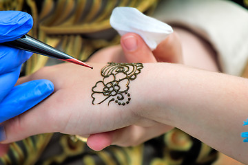 Image showing A tattoo artist applying his craft onto the hand of a female