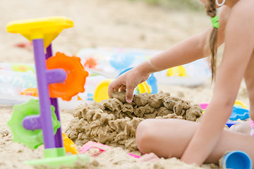 Image showing The girl builds a sand castle wall