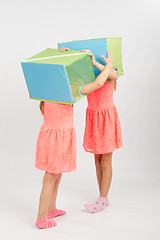 Image showing Two girls play about putting on a head box