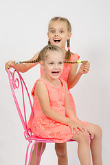 Image showing Girl having fun holding the other girl braids hair