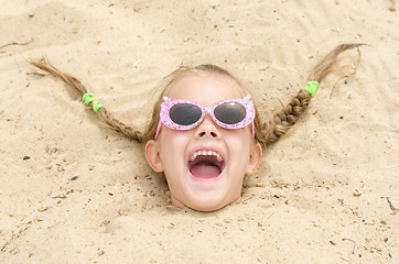 Image showing Five-year girl with glasses on a beach strewn on his head in the sand