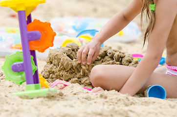 Image showing The girl builds a sand castle