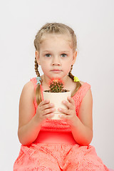 Image showing Girl holding a cactus keeps