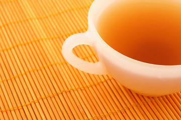 Image showing Cup of tea on orange rattan mat