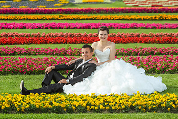 Image showing Bride and groom posing on lawn with flowers