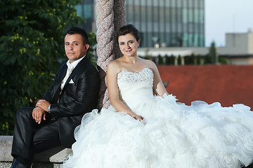 Image showing Newlyweds sitting on wall