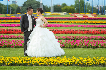 Image showing Bride and groom standing on lawn with flowers