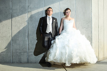 Image showing Bride and groom posing in front of wall