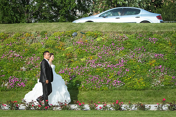 Image showing Newlyweds walking on pathway with flowers