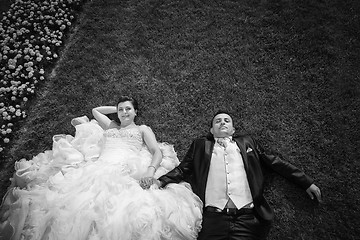 Image showing Bride and groom holding hands on lawn with flowers bw