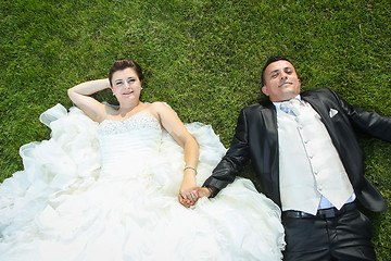 Image showing Bride and groom holding hands on lawn