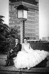 Image showing Newlyweds sitting next to street lamp bw