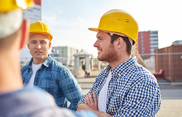 Image showing group of smiling builders in hardhats outdoors