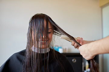 Image showing happy woman with stylist cutting hair at salon