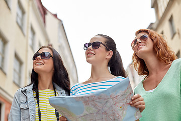 Image showing smiling teenage girls with map and camera outdoors