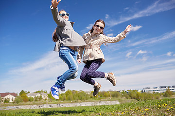 Image showing happy little girls jumping high outdoors