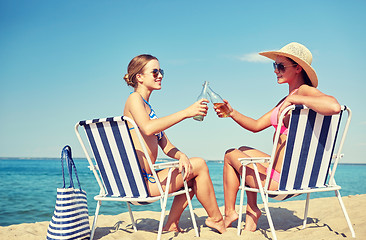 Image showing happy women clinking bottles and drinking on beach