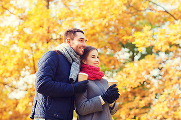 Image showing smiling couple with coffee cups in autumn park