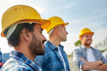 Image showing group of smiling builders in hardhats outdoors