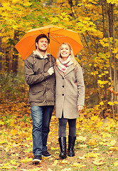 Image showing smiling couple with umbrella in autumn park