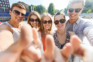 Image showing happy friends taking selfie and showing thumbs up