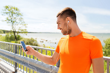 Image showing smiling young man with smartphone and earphones