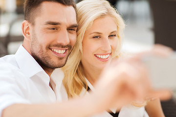 Image showing happy couple taking selfie with smatphone outdoors